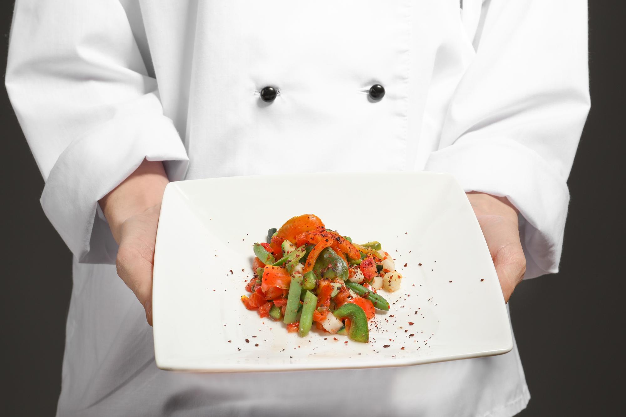 Chef demonstrates fine plating in a warm kitchen